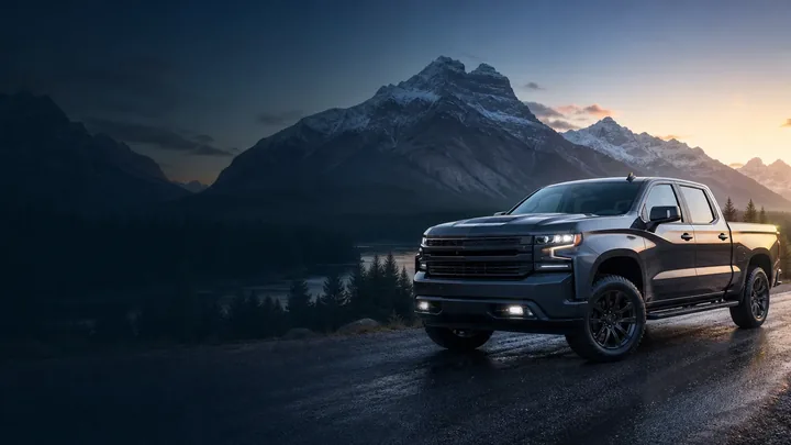 Dark graphite pickup truck beside a mountain lake